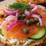 Smoked salmon bagel sandwich layered with cream cheese, red onion, cucumber, capers, and fresh dill