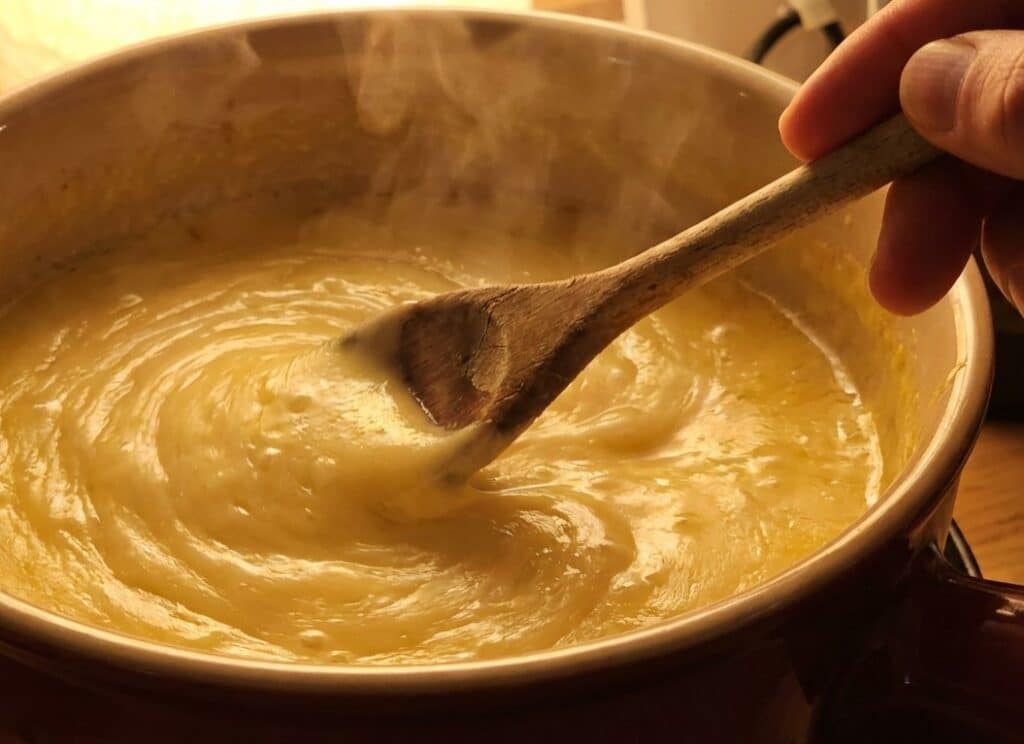 stirring smooth cheese fondue recipe in pot