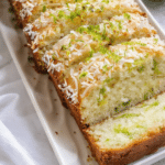 Moist Tropical Coconut Lime Cake sliced on plate with fresh lime zest