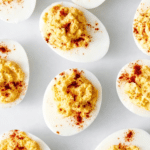 Easy deviled eggs with creamy yolk filling and paprika garnish on a serving platter