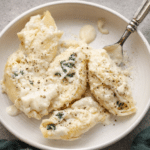 Creamy Alfredo stuffed shells baked with ricotta cheese and spinach in a casserole dish