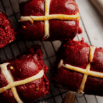 Close-up of soft red velvet hot cross buns with chocolate chips and shiny glaze
