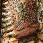 Garlic roasted rack of lamb with butter sauce and fresh herbs on a serving plate