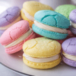 Pastel sugar cookie sandwiches with vanilla buttercream filling on a spring dessert plate
