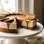 Biscoff cheesecake with cookie butter drizzle on a white cake stand