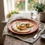 Harissa eggs with whipped goat cheese on a terracotta plate with fresh herbs