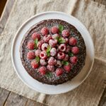 gluten free chocolate cake recipe without eggs on white cake stand with raspberries